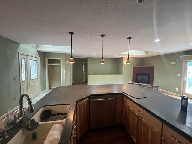72 E Brink St, Grant, MI 49327 - kitchen with a sink, a fireplace, dark countertops, dishwasher, and hanging light fixtures