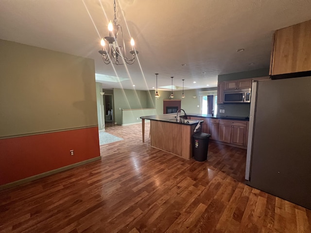 72 E Brink St, Grant, MI 49327 - kitchen featuring stainless steel appliances, dark countertops, dark wood-style flooring, an island with sink, and a chandelier