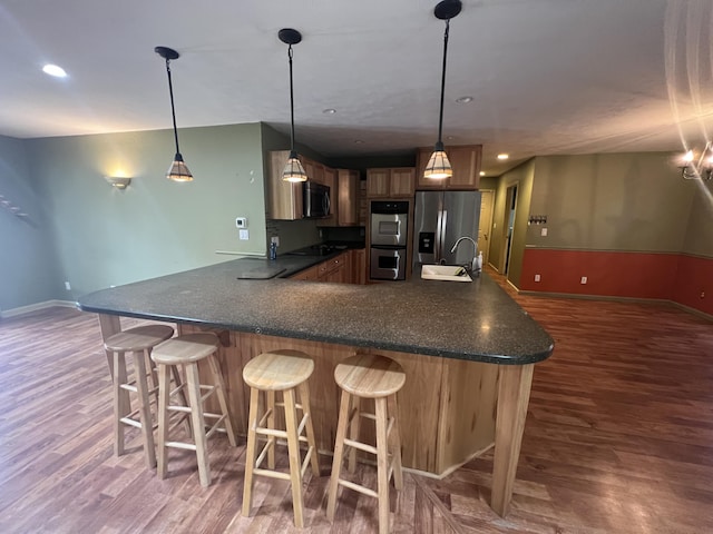 72 E Brink St, Grant, MI 49327 - kitchen with stainless steel appliances, dark wood-style flooring, a sink, baseboards, and a kitchen bar