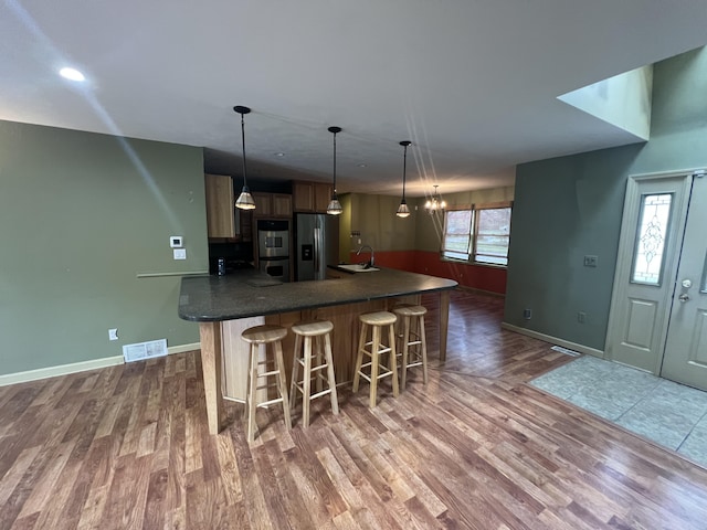 72 E Brink St, Grant, MI 49327 - kitchen with stainless steel appliances, a sink, wood finished floors, dark countertops, and a kitchen breakfast bar