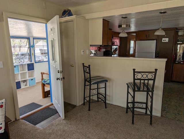 5268 S Arrowhead Trl, Baldwin, MI 49304 - kitchen featuring freestanding refrigerator, carpet flooring, a breakfast bar, a peninsula, and decorative light fixtures