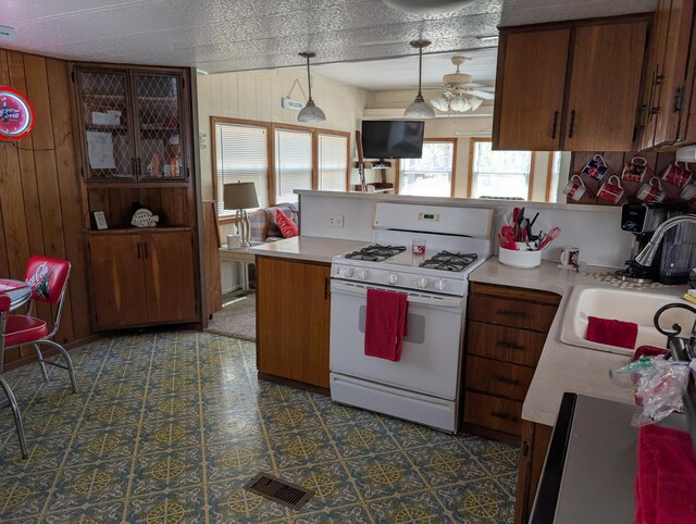 5268 S Arrowhead Trl, Baldwin, MI 49304 - kitchen featuring white gas range oven, light countertops, a peninsula, wooden walls, and a sink