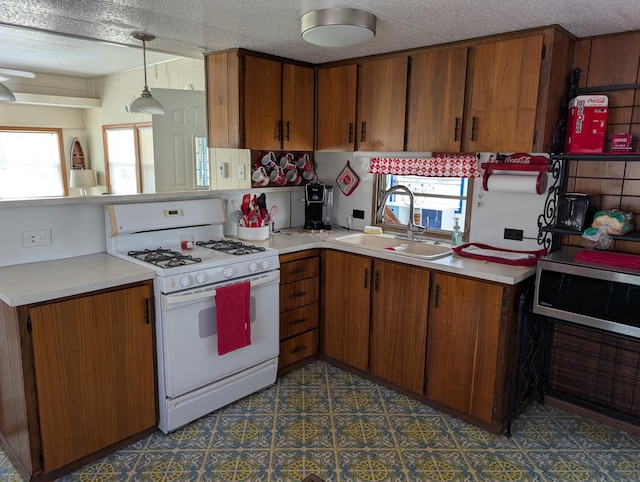 5268 S Arrowhead Trl, Baldwin, MI 49304 - kitchen featuring white gas stove, a sink, stainless steel microwave, brown cabinetry, and light countertops