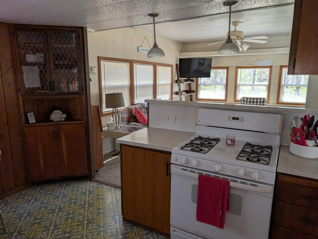 5268 S Arrowhead Trl, Baldwin, MI 49304 - kitchen with gas range gas stove, ceiling fan, light countertops, pendant lighting, and wooden walls