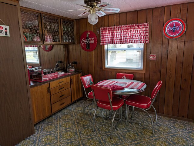 5268 S Arrowhead Trl, Baldwin, MI 49304 - dining area with a ceiling fan, wood walls, and dark flooring