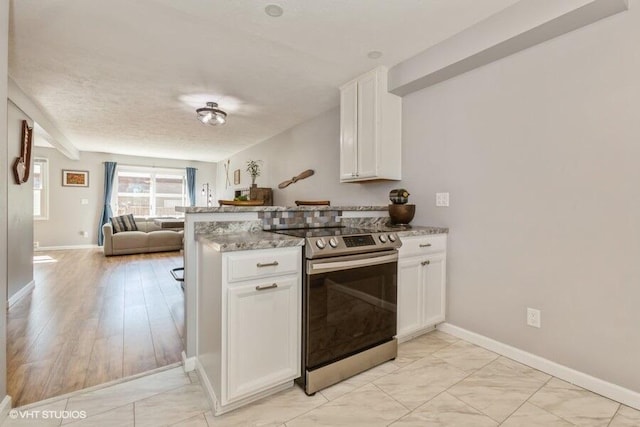 2553 Bristol Ter, Saint Joseph, MI 49085 - kitchen with stainless steel range with electric stovetop, open floor plan, light marble finish flooring, a peninsula, and white cabinetry