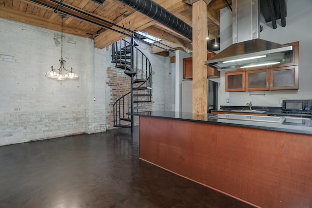 6533 E Jefferson Ave Unit 413W, Detroit, MI 48207 - kitchen with island range hood, brick wall, a sink, dark countertops, and brown cabinets