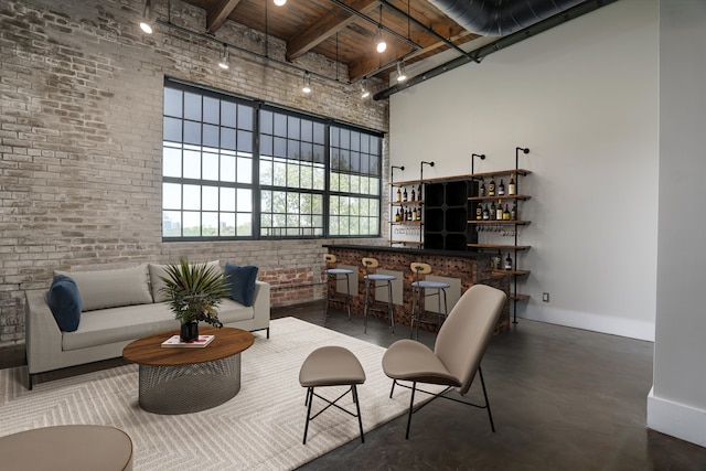 6533 E Jefferson Ave Unit 413W, Detroit, MI 48207 - living area with a towering ceiling, baseboards, concrete floors, brick wall, and a dry bar