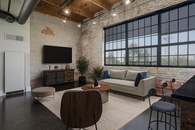 6533 E Jefferson Ave Unit 413W, Detroit, MI 48207 - living area with wooden ceiling with exposed beams, track lighting, brick wall, a high ceiling, and finished concrete flooring