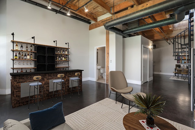 6533 E Jefferson Ave Unit 413W, Detroit, MI 48207 - living area with a dry bar, rail lighting, baseboards, a high ceiling, and wooden ceiling with exposed beams