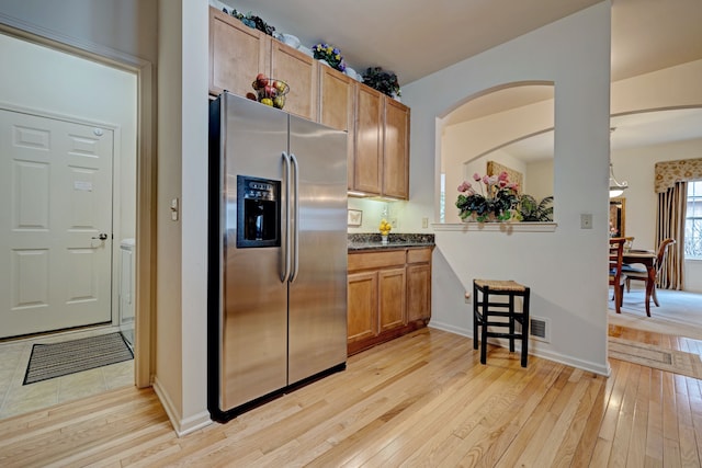 6927 Stonewood Pl, Clarkston, MI 48346 - kitchen featuring stainless steel refrigerator with ice dispenser, light wood finished floors, dark countertops, baseboards, and arched walkways