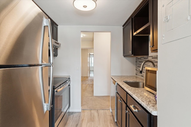 555 E William St Unit 10D, Ann Arbor, MI 48104 - kitchen featuring appliances with stainless steel finishes, a sink, light wood finished floors, dark brown cabinets, and decorative backsplash