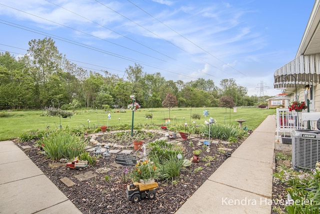 view of green lawn with central AC unit and view of scattered trees