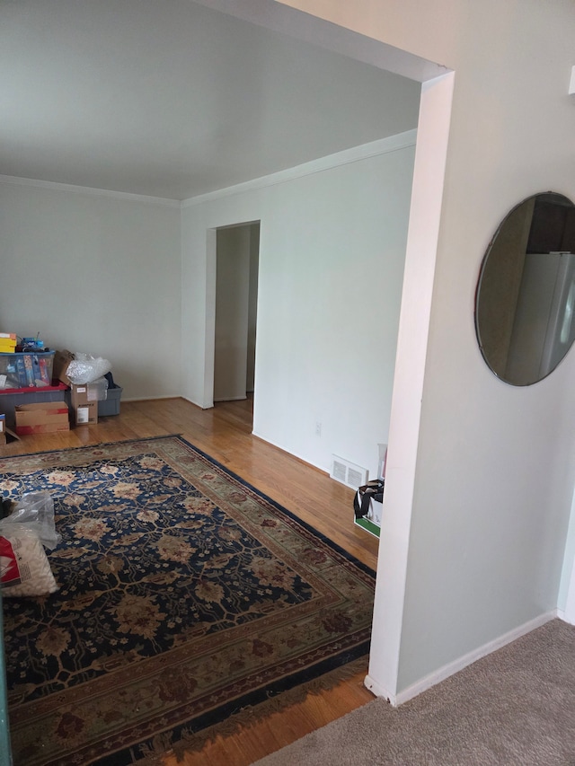 interior space featuring wood finished floors, ornamental molding, and baseboards