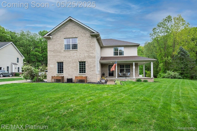 2038 Pine Bluffs Ct, Highland, MI 48357 - rear view of property featuring brick siding, a porch, and a lawn
