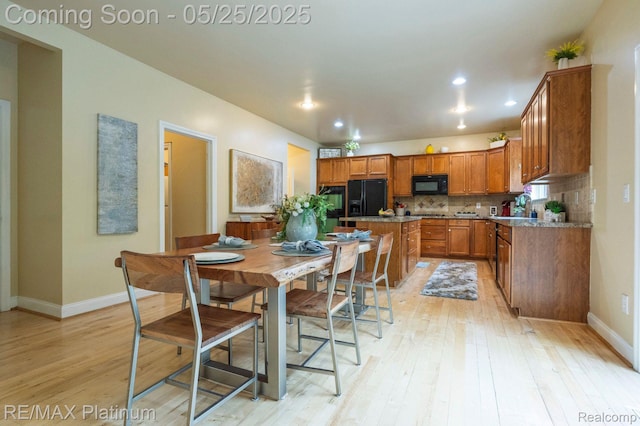 2038 Pine Bluffs Ct, Highland, MI 48357 - kitchen featuring black appliances, brown cabinets, light wood-type flooring, baseboards, and decorative backsplash