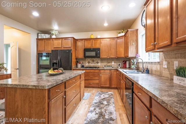 2038 Pine Bluffs Ct, Highland, MI 48357 - kitchen featuring black appliances, light wood finished floors, a sink, brown cabinetry, and a kitchen island