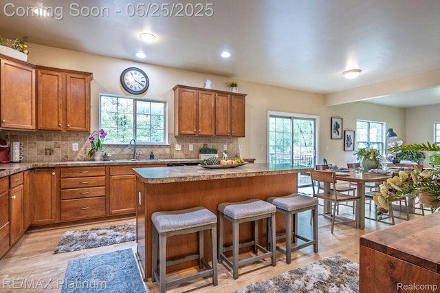 2038 Pine Bluffs Ct, Highland, MI 48357 - kitchen featuring a sink, brown cabinetry, a center island, a breakfast bar area, and recessed lighting