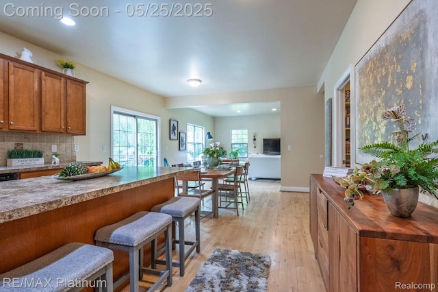 2038 Pine Bluffs Ct, Highland, MI 48357 - kitchen with brown cabinetry, light wood-type flooring, a kitchen bar, backsplash, and recessed lighting