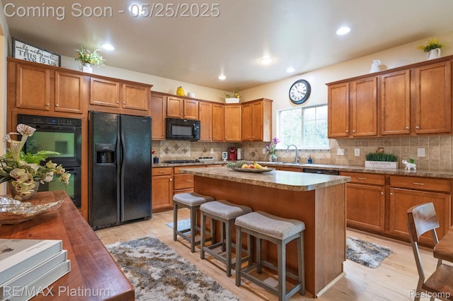 2038 Pine Bluffs Ct, Highland, MI 48357 - kitchen featuring black appliances, brown cabinetry, light wood-style flooring, a center island, and recessed lighting