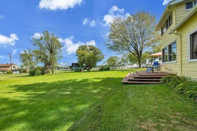 view of green lawn featuring a deck