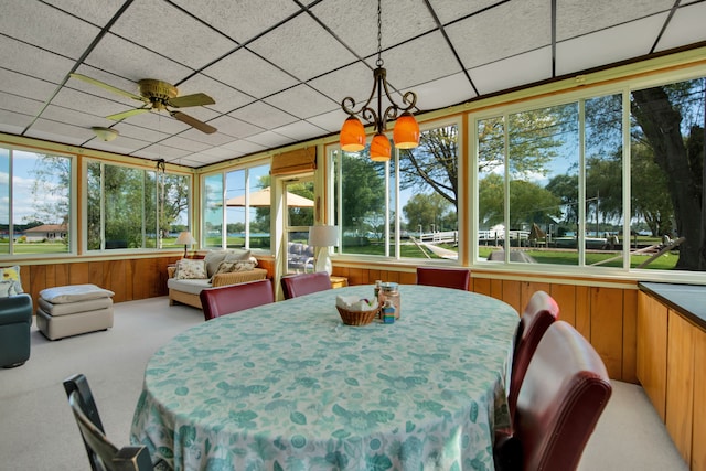 sunroom featuring carpet floors, wood walls, plenty of natural light, and a paneled ceiling