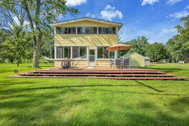 rear view of house with a deck, a yard, a shed, and an outbuilding