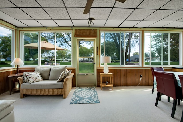 sunroom / solarium featuring carpet floors, healthy amount of natural light, and wood walls