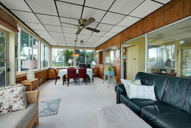 sunroom / solarium with an outdoor hangout area, a ceiling fan, outdoor dining space, carpet flooring, and wooden walls