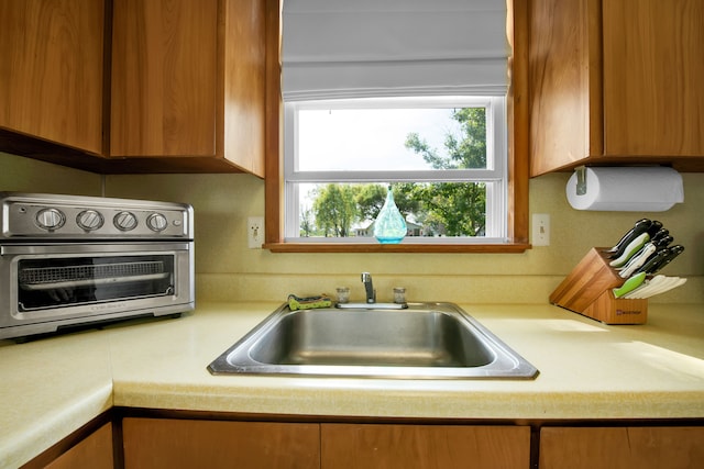 kitchen with a sink, light countertops, and brown cabinets