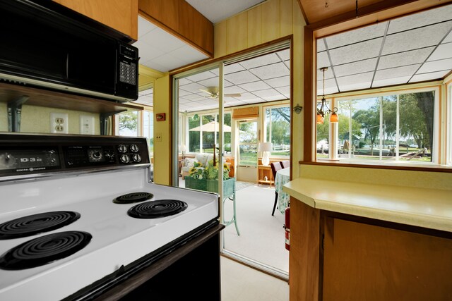 kitchen with range with electric stovetop, black microwave, healthy amount of natural light, and light countertops
