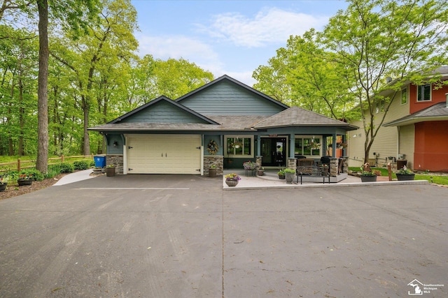 2307 Tecumseh Dr, Brooklyn, MI 49230 - view of front facade featuring a garage, driveway, a shingled roof, and stone siding