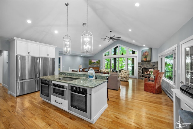 2307 Tecumseh Dr, Brooklyn, MI 49230 - kitchen featuring stainless steel appliances, vaulted ceiling, open floor plan, white cabinets, and a fireplace