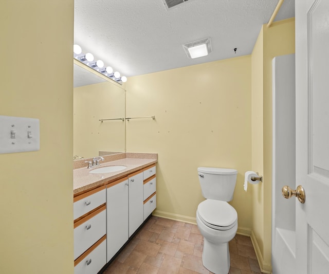 1379 Millbrook Trl, Ann Arbor, MI 48108 - bathroom with stone tile floors, toilet, vanity, baseboards, and a textured ceiling