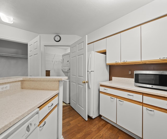 1379 Millbrook Trl, Ann Arbor, MI 48108 - kitchen with stacked washer / drying machine, white appliances, dark wood-style floors, light countertops, and white cabinets
