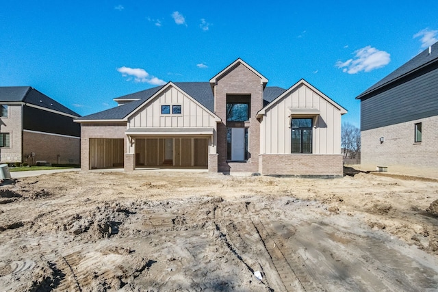 45070 Twin River Dr, Macomb, MI 48044 - view of front facade featuring board and batten siding, brick siding, and a garage