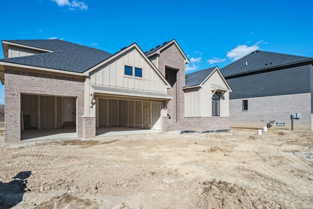 45070 Twin River Dr, Macomb, MI 48044 - back of house with board and batten siding, brick siding, an attached garage, and a shingled roof