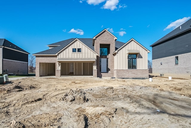 45070 Twin River Dr, Macomb, MI 48044 - view of front of house featuring board and batten siding, an attached garage, and brick siding