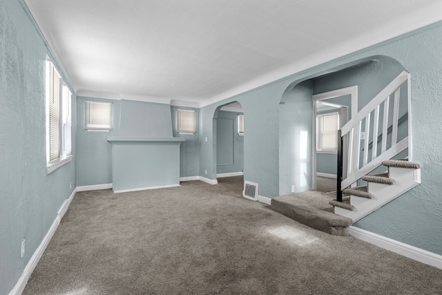 15748 Freeland St, Detroit, MI 48227 - unfurnished living room featuring a textured wall, arched walkways, carpet floors, and baseboards