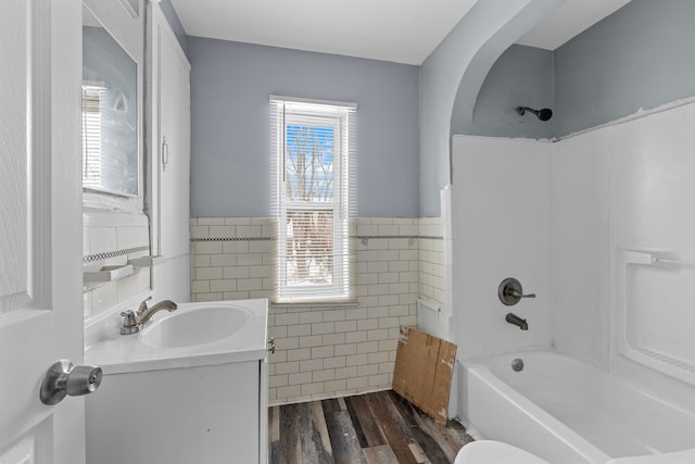 15748 Freeland St, Detroit, MI 48227 - bathroom with tile walls, wood finished floors, shower / tub combination, vanity, and a wainscoted wall