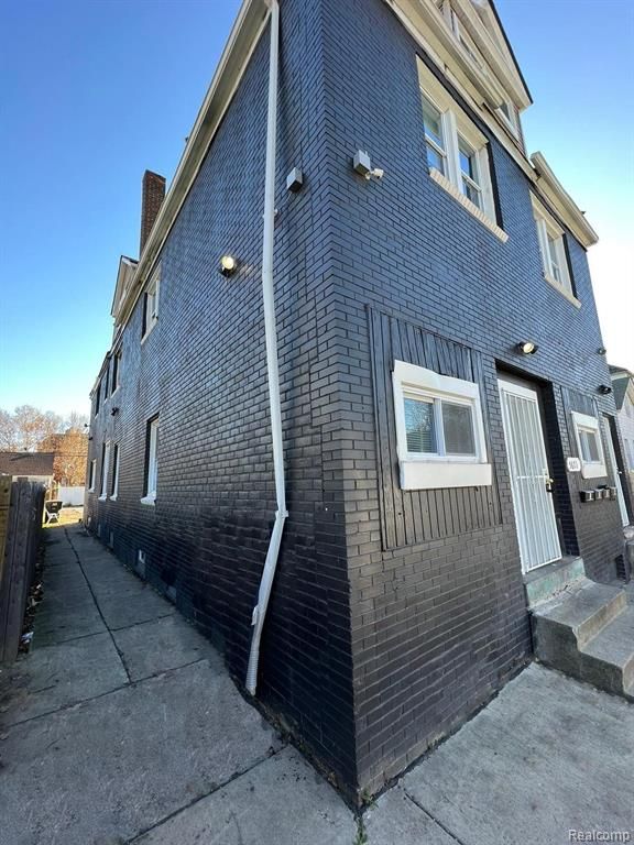 5671 Otis St, Detroit, MI 48210 - view of side of property featuring brick siding, a chimney, fence, and entry steps