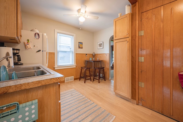406 Common St, Walled Lake, MI 48390 - kitchen featuring a wainscoted wall, light wood finished floors, ceiling fan, a sink, and arched walkways