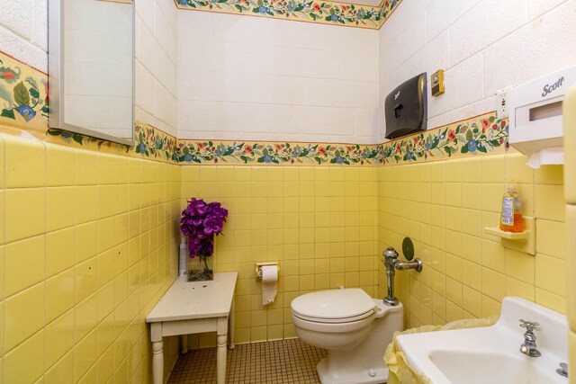 20800 Lefever Ave, Warren, MI 48091 - bathroom with tile walls, tile patterned floors, toilet, a sink, and a wainscoted wall