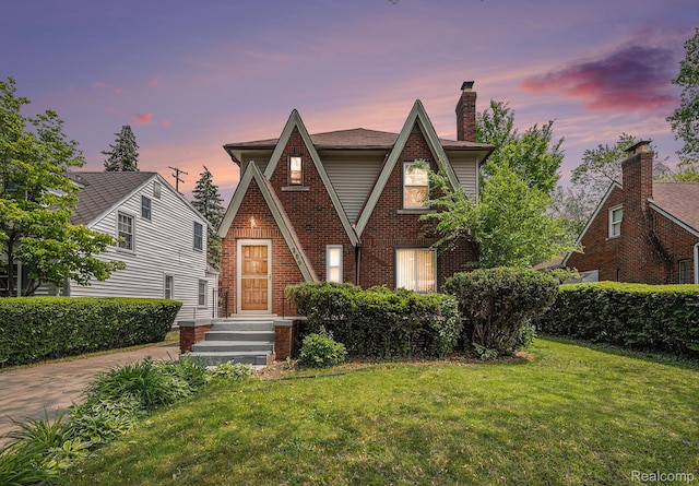 259 Navajo Ave, Pontiac, MI 48341 - tudor house featuring a front lawn, brick siding, and a chimney