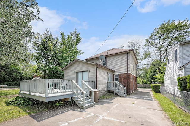 259 Navajo Ave, Pontiac, MI 48341 - back of house featuring driveway, a wooden deck, and brick siding
