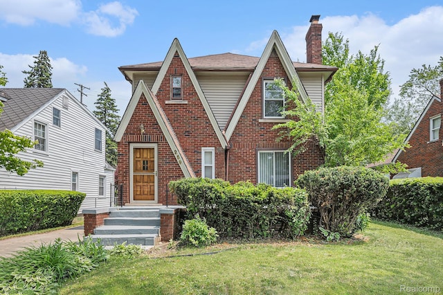 259 Navajo Ave, Pontiac, MI 48341 - tudor home featuring a front yard, a chimney, and brick siding