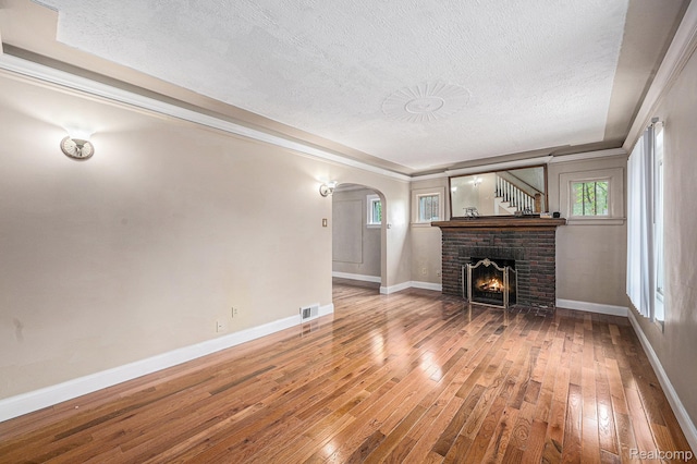 259 Navajo Ave, Pontiac, MI 48341 - unfurnished living room featuring a textured ceiling, arched walkways, hardwood / wood-style flooring, baseboards, and crown molding