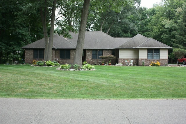 view of front facade featuring brick siding, a front lawn, and a shingled roof