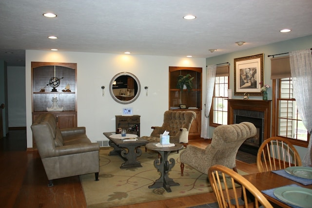 living area with wood finished floors, a tile fireplace, and recessed lighting
