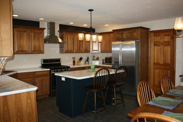 kitchen featuring stainless steel appliances, wall chimney range hood, dark tile patterned flooring, light countertops, and decorative backsplash